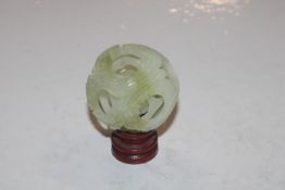 A carved jade coloured puzzle ball on wooden stand