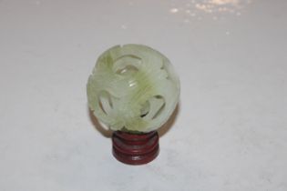 A carved jade coloured puzzle ball on wooden stand