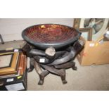 A decorative bowl on figural hardwood stand