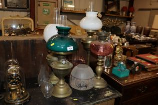 Four brass oil lamps, one with cranberry glass res