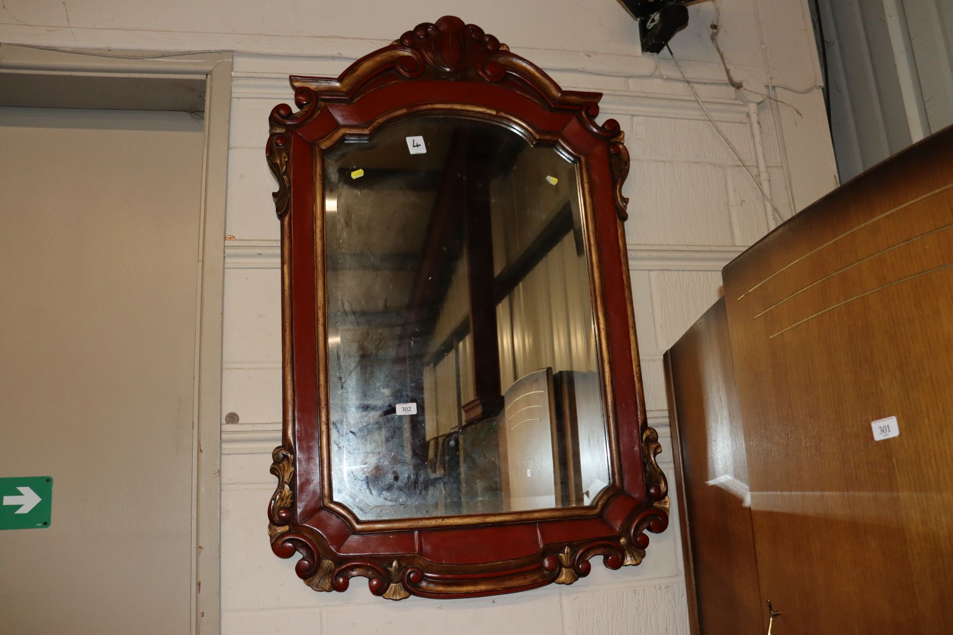 A red painted and gilt bevel edged wall mirror, me