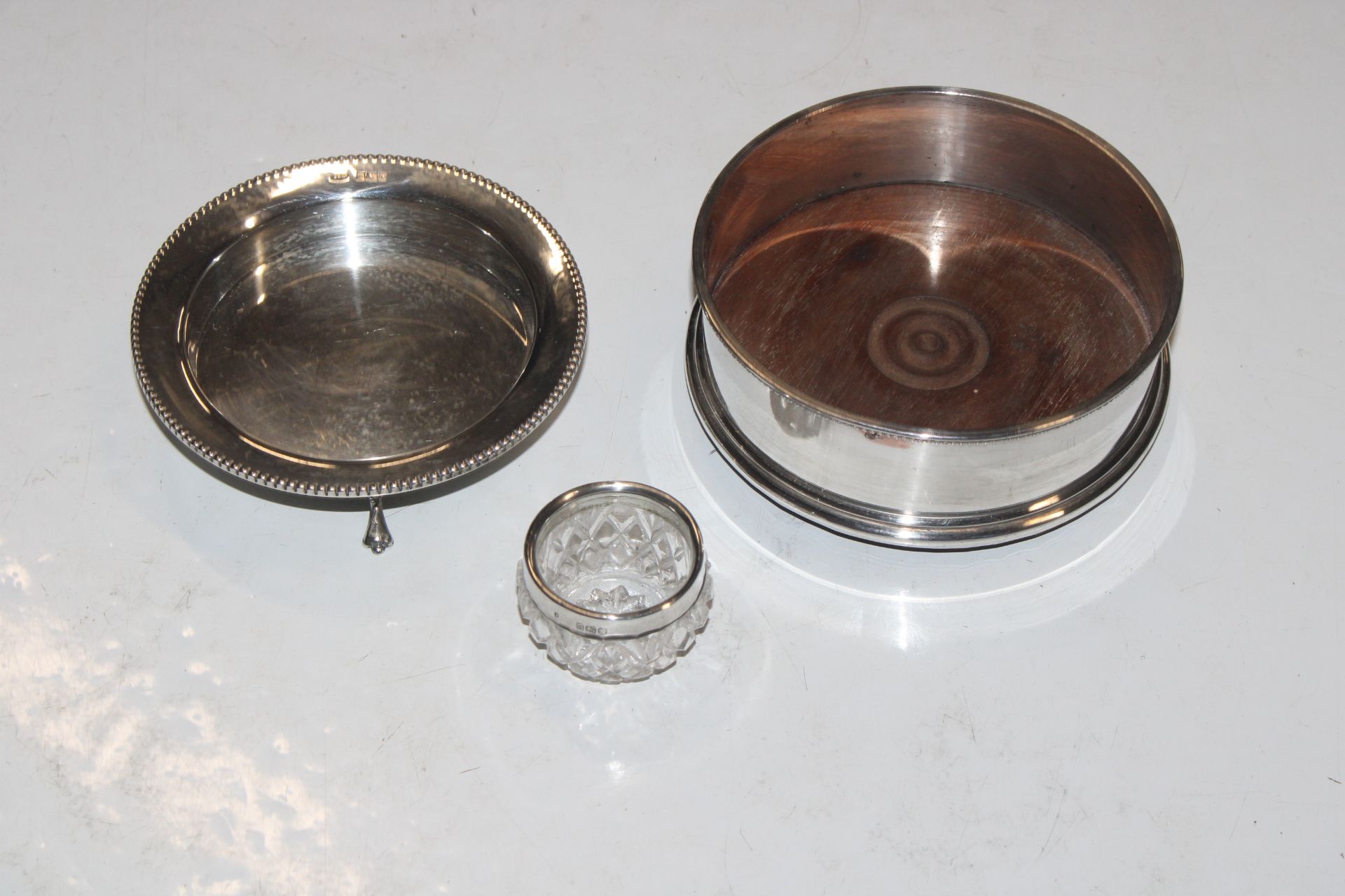 A circular silver dish raised on three supports, a