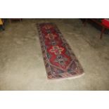 An approx. 9'4" x 2'7" red and blue patterned rug