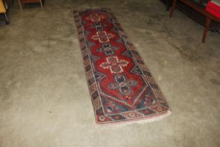 An approx. 9'4" x 2'7" red and blue patterned rug