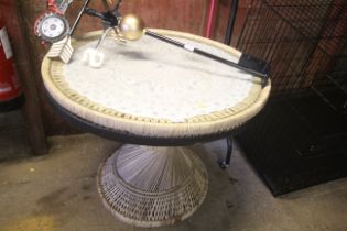 A circular wicker table on spiral base with glass