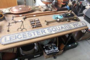 A wooden sign "Leicester Square WC2"
