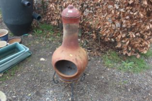 A terracotta chimenea on wrought metal tripod base