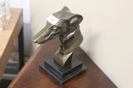 A bronzed greyhound head ornament on granite base
