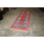 An approx. 10'6" x 3'4" red patterned rug AF