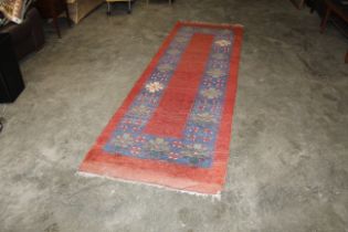 An approx. 10'6" x 3'4" red patterned rug AF