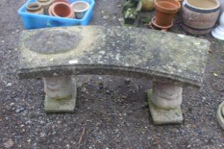 A concrete two seater garden seat on concrete squi