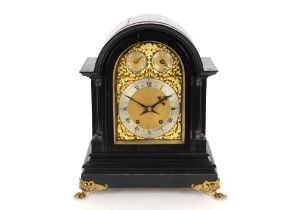 A 19th Century ebonised table clock, the arched case supporting an ornate foliate brass dial with