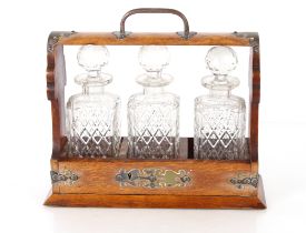 A late Victorian oak and electroplate mounted three bottle Tantalus