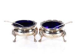 A pair of mid-Victorian silver table salts, raised on hoof feet with blue glass liners; and two