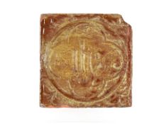 A Medieval period encaustic floor tile with inscription "I.H.S." 11.5cm sq.