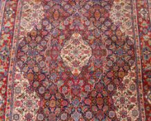 A Persian wool rug, having all over foliate design on predominantly red and blue ground, 218cm x