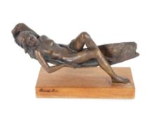 A bronze sculpture of a reclining nude, 45cm long raised on a wooden plinth indistinctly signed,
