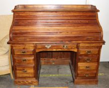 A large Colonial hardwood roll top desk, having a fitted interior arrangement of pigeon holes and