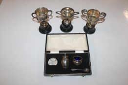 Three silver trophy cups and a part cruet set, we