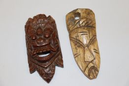 A small carved wooden face mask and a carved bone