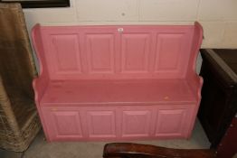 A pink painted settle with lift-up seat storage co
