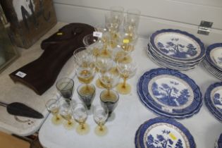 A collection of yellow tinted glasses including champagne coupes, wines and liquors etc