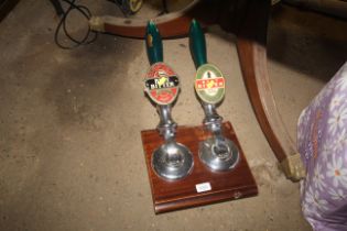 Two beer pumps mounted to wooden board