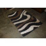 A black, white and brown patterned wool rug approx