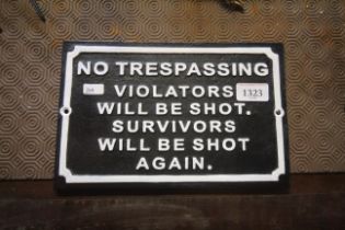 A painted cast iron sign for "No Trespassing, Violators Will Be Shot. Survivors Will Be shot