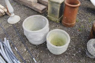 A graduated pair of concrete planters decorated wi