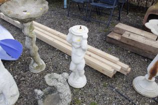 A bird bath raised on cherub plinth