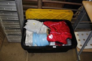 A plastic crate of various dog toys, coats and lea