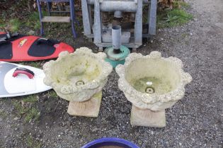 A pair of concrete garden urns raised on plinths