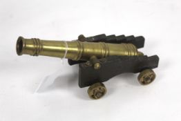 A small model brass cannon on wooden carriage, bar