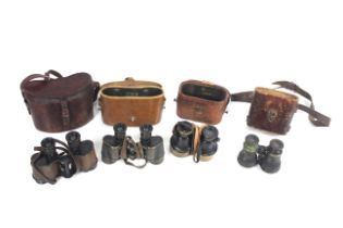 Four pairs of WWII era binoculars , with their lea
