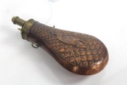 A copper powder flask with embossed boar and arms