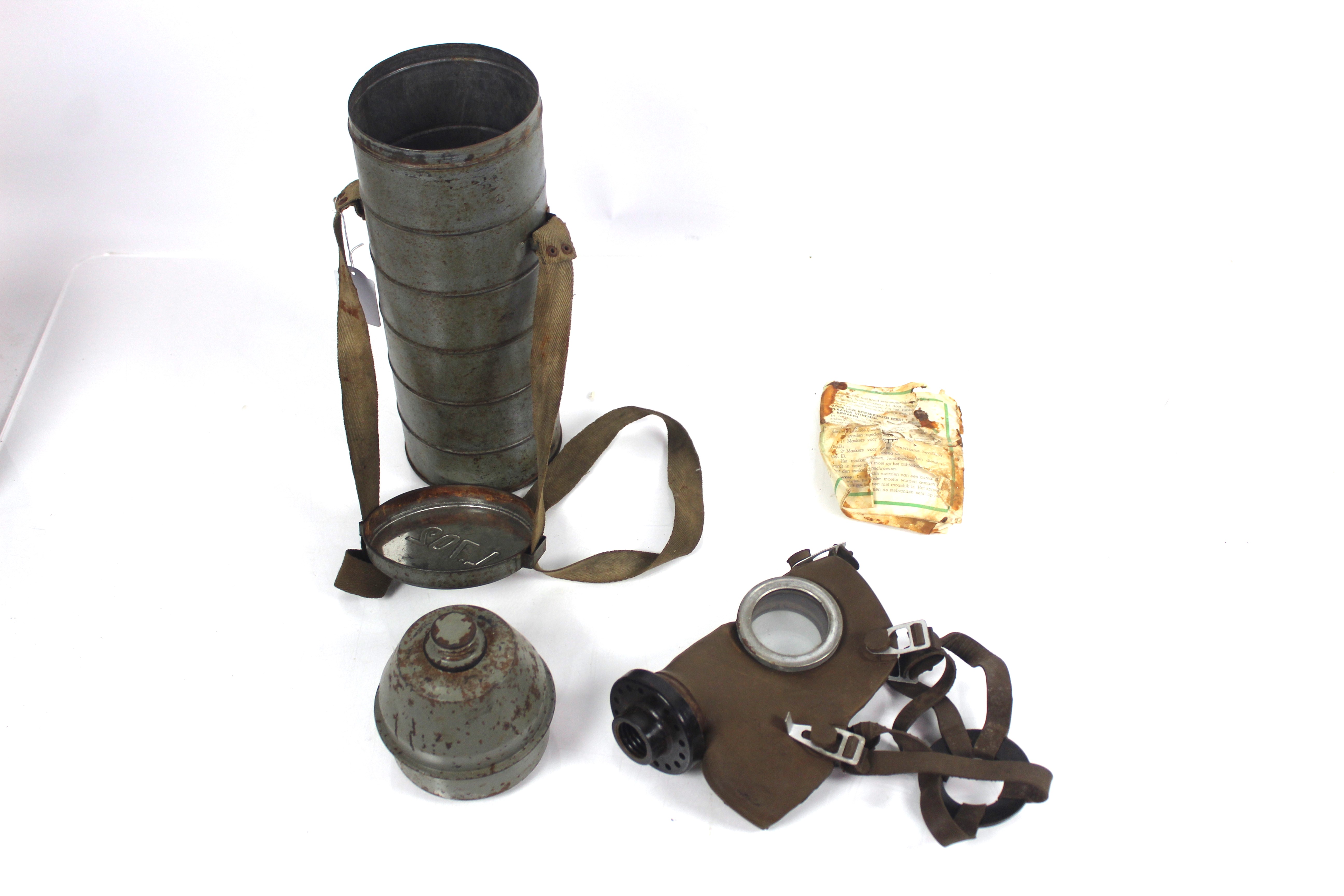 A WWII era Belgium gas mask within long tin