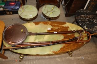 An antique copper warming pan with turned wooden h