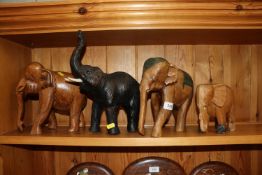 Three carved elephant ornaments and a leather clad