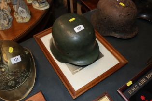 A German WWII helmet with framed portrait of a Ger