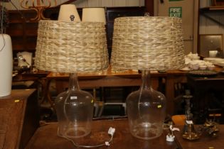 A pair of glass bottle table lamps with wicker sha