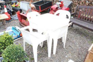 A white plastic garden table and a set of four mat