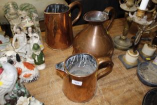 A copper 1 gallon measure and two copper jugs