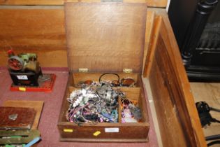 A wooden box with contents of various costume jewe