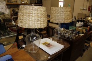 A pair of glass bottle table lamps with wicker sha