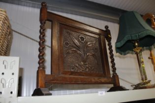 A 1930s carved oak fire screen