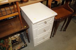 A cream three drawer bedside cabinet