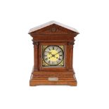 A late Victorian oak cased mantel clock, the case of architectural design enclosing a brass and