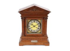 A late Victorian oak cased mantel clock, the case of architectural design enclosing a brass and