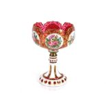 A 19th Century ruby glass overlaid pedestal bowl, the panels with profuse foliate decoration on gilt
